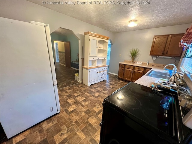 kitchen featuring white fridge, black range with electric stovetop, a textured ceiling, and sink