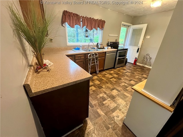 kitchen with appliances with stainless steel finishes, a textured ceiling, and sink