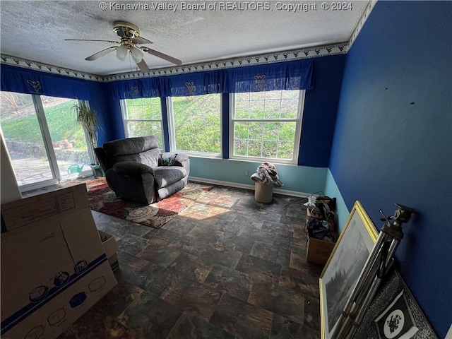 living room featuring ceiling fan and a textured ceiling