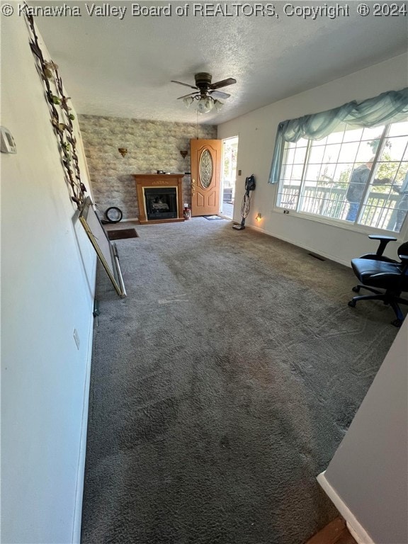 unfurnished living room with ceiling fan, a textured ceiling, and carpet floors