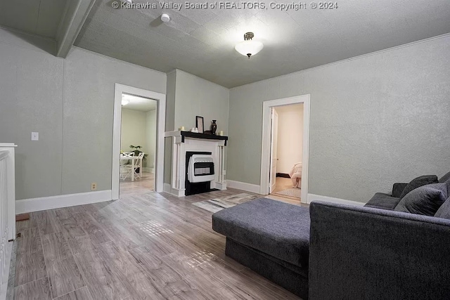 living room with a textured ceiling, beamed ceiling, a fireplace, wood-type flooring, and heating unit