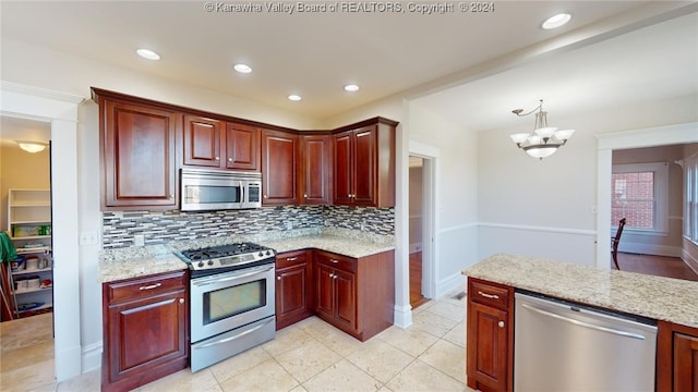 kitchen with light stone countertops, stainless steel appliances, a notable chandelier, decorative light fixtures, and decorative backsplash