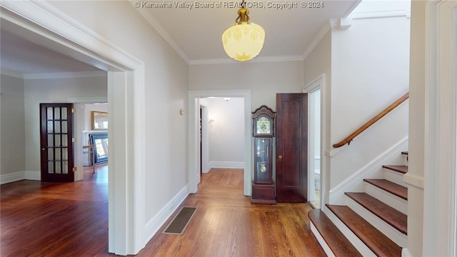 entrance foyer featuring a notable chandelier, ornamental molding, and dark wood-type flooring