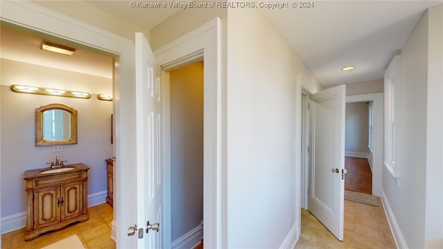 corridor featuring light tile patterned floors and sink