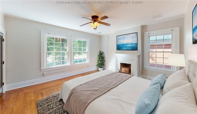 bedroom with multiple windows, ceiling fan, and hardwood / wood-style flooring