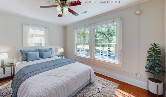 bedroom featuring hardwood / wood-style flooring, ceiling fan, and crown molding