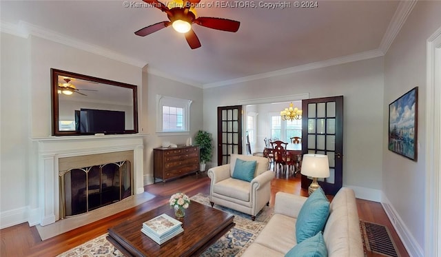 living room featuring wood-type flooring, ceiling fan with notable chandelier, and ornamental molding