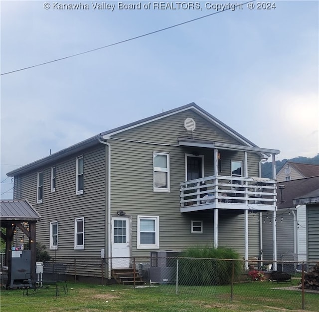 rear view of house with a balcony and a lawn