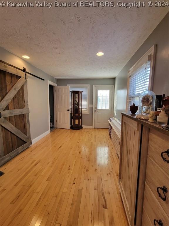 interior space featuring a textured ceiling, a barn door, and light hardwood / wood-style flooring