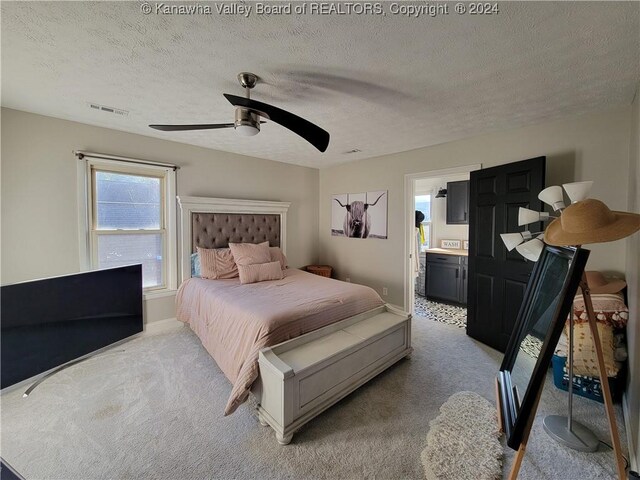 bedroom with a textured ceiling, ensuite bathroom, ceiling fan, and carpet flooring