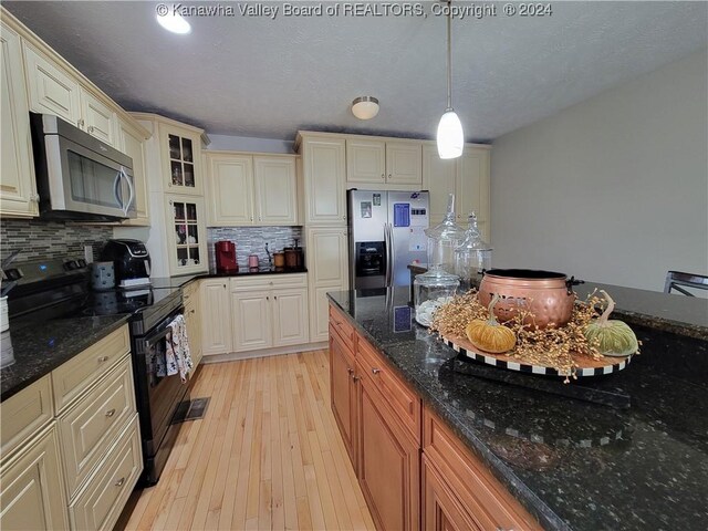 kitchen featuring dark stone countertops, backsplash, stainless steel appliances, light hardwood / wood-style floors, and a textured ceiling