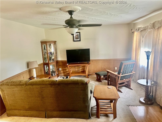 carpeted living room with ceiling fan, wooden walls, and a textured ceiling