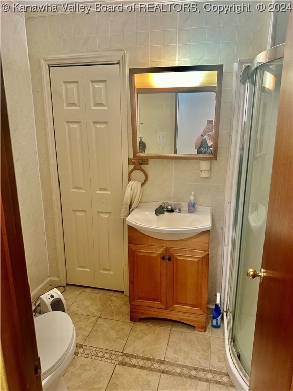 bathroom with tile patterned floors, toilet, tile walls, a shower with shower door, and vanity