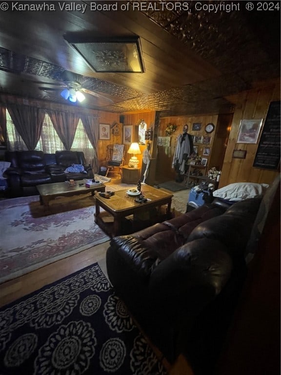 living room with wood walls, ceiling fan, and wood-type flooring