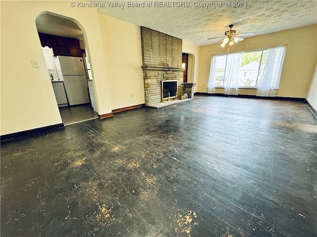 unfurnished living room with a fireplace, a textured ceiling, and ceiling fan