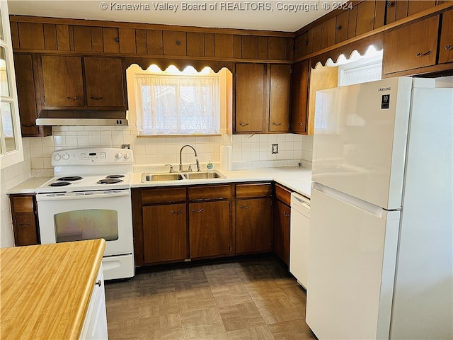 kitchen featuring white appliances, a healthy amount of sunlight, backsplash, and sink