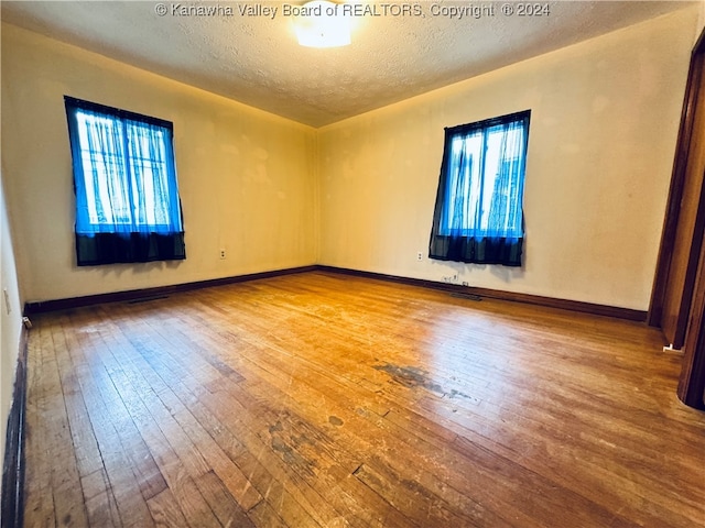 unfurnished room with wood-type flooring, plenty of natural light, and a textured ceiling