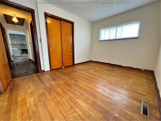 unfurnished bedroom with a large fireplace, a closet, and wood-type flooring