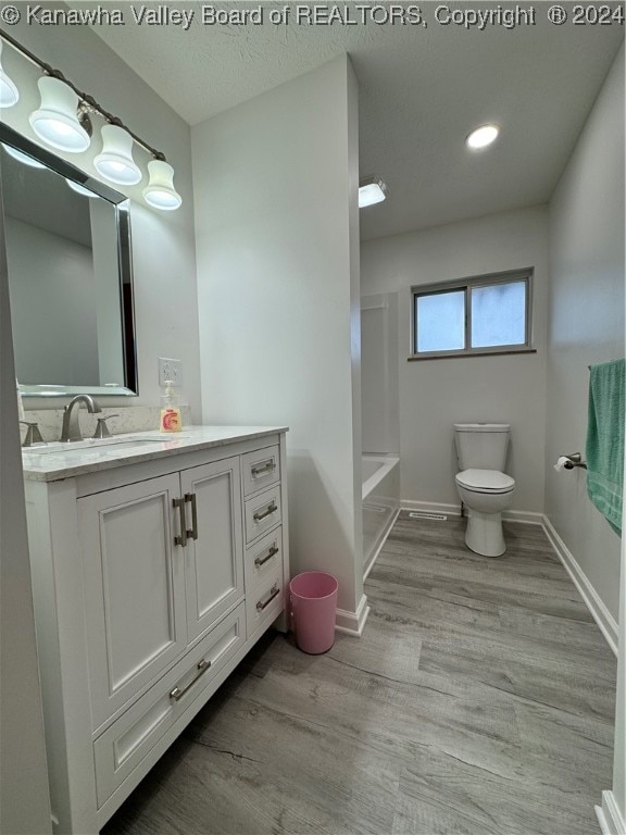 bathroom featuring toilet, hardwood / wood-style flooring, a textured ceiling, and vanity