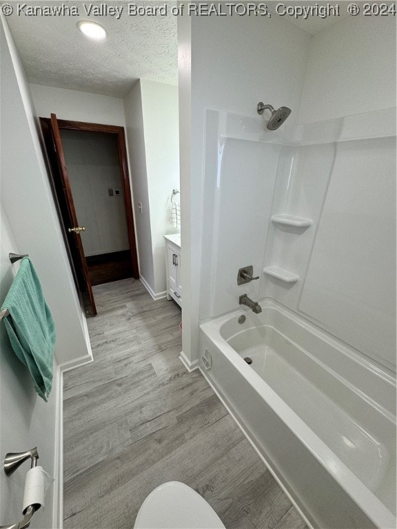 full bathroom with hardwood / wood-style flooring, a textured ceiling, toilet, shower / bath combination, and vanity