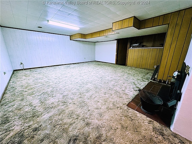 basement featuring wood walls and dark colored carpet