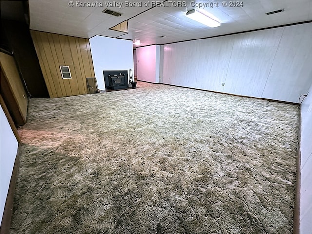 unfurnished living room with carpet and wood walls