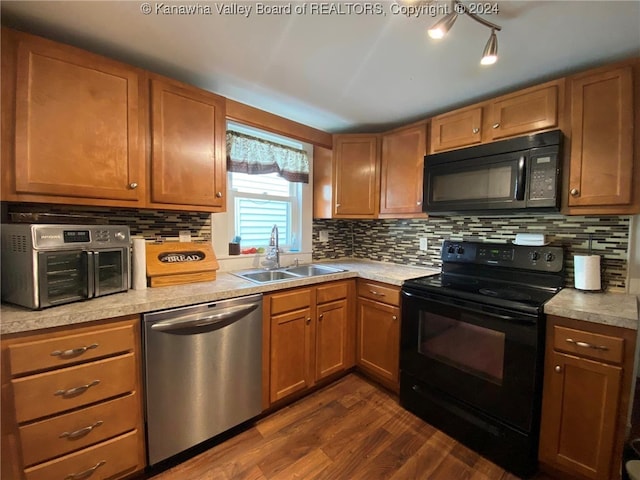 kitchen featuring black appliances, sink, dark wood-type flooring, and decorative backsplash