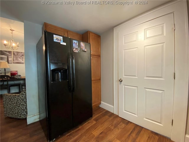 kitchen featuring dark wood-type flooring, decorative light fixtures, a chandelier, and black refrigerator with ice dispenser