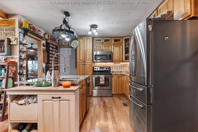 kitchen featuring a textured ceiling, light wood-type flooring, sink, and appliances with stainless steel finishes