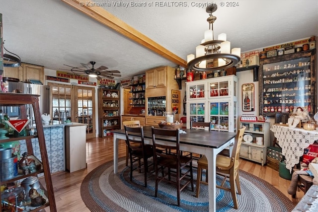 dining space with ceiling fan with notable chandelier, light wood-type flooring, a textured ceiling, and a healthy amount of sunlight