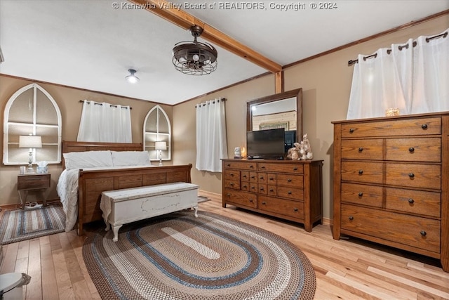 bedroom with beamed ceiling and light hardwood / wood-style floors