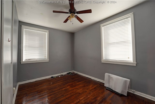 empty room with plenty of natural light, ceiling fan, and dark wood-type flooring