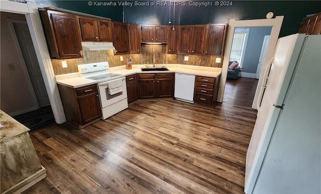 kitchen featuring backsplash, white appliances, sink, wood-type flooring, and dark brown cabinets