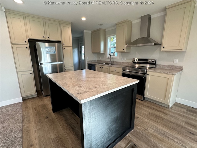 kitchen featuring hardwood / wood-style flooring, appliances with stainless steel finishes, sink, wall chimney range hood, and a kitchen island