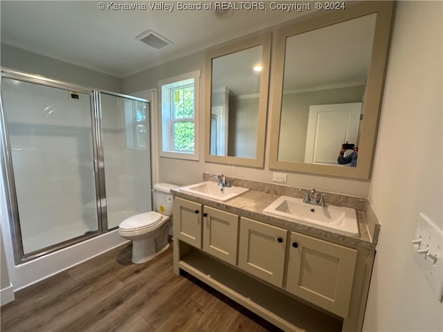 bathroom featuring a shower with door, vanity, hardwood / wood-style floors, toilet, and ornamental molding