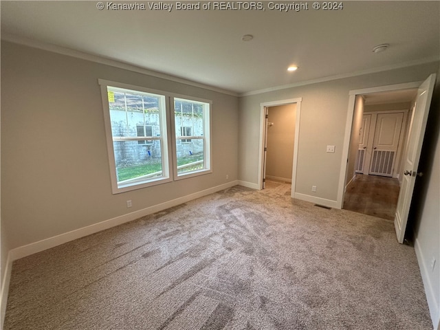 unfurnished bedroom featuring ornamental molding, light colored carpet, a walk in closet, and a closet