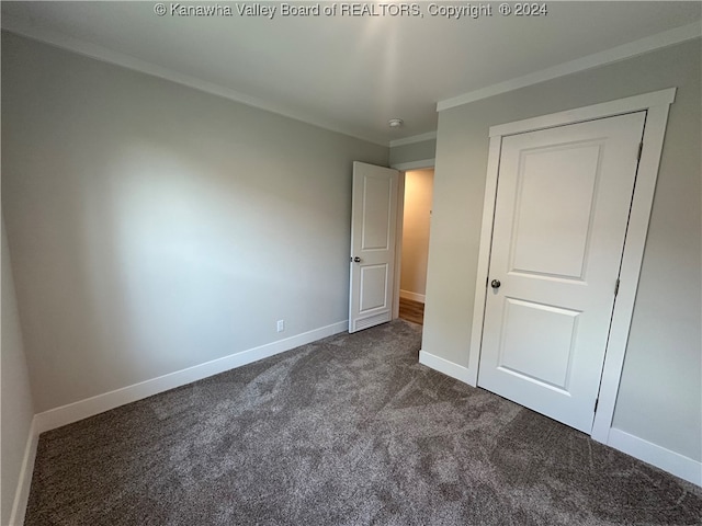 unfurnished bedroom featuring dark carpet and ornamental molding