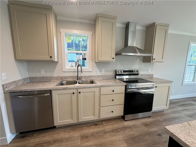 kitchen featuring crown molding, light wood-type flooring, appliances with stainless steel finishes, sink, and wall chimney range hood