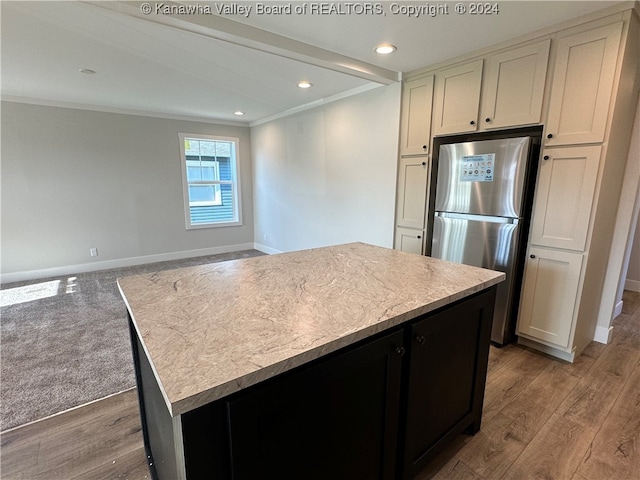 kitchen with crown molding, a kitchen island, stainless steel refrigerator, and light wood-type flooring