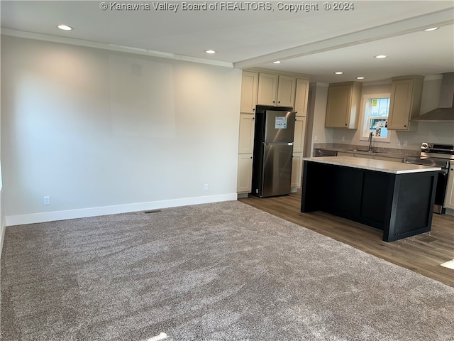 kitchen with a center island, hardwood / wood-style floors, stainless steel appliances, sink, and wall chimney exhaust hood