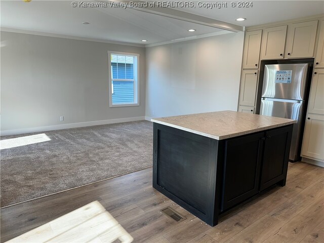 kitchen with stainless steel refrigerator, cream cabinetry, crown molding, light hardwood / wood-style flooring, and a kitchen island