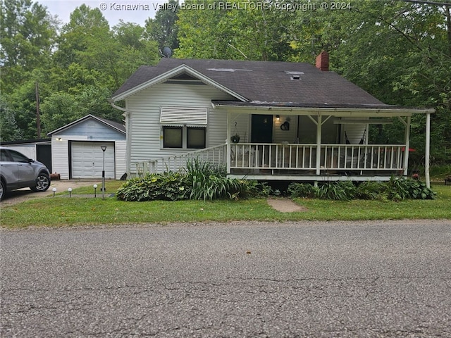 view of front of property featuring covered porch, an outbuilding, a garage, and a front lawn