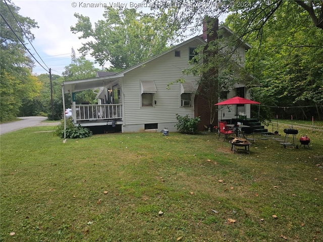 back of property with a fire pit and a lawn