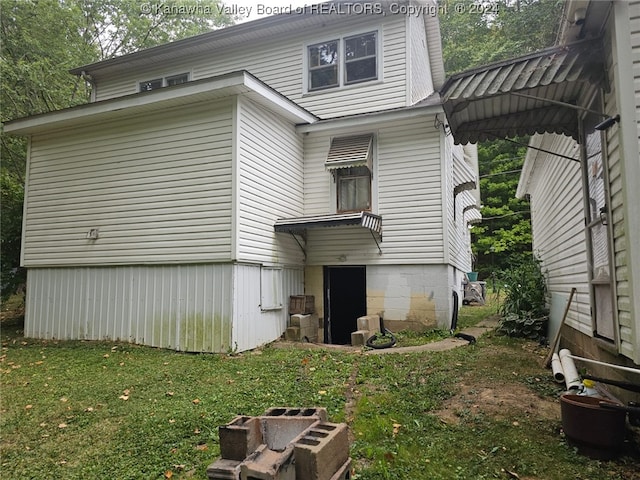 back of house featuring an outdoor fire pit and a lawn