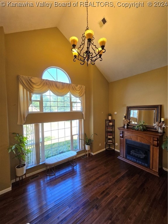 unfurnished living room featuring dark wood-type flooring, high vaulted ceiling, and a chandelier