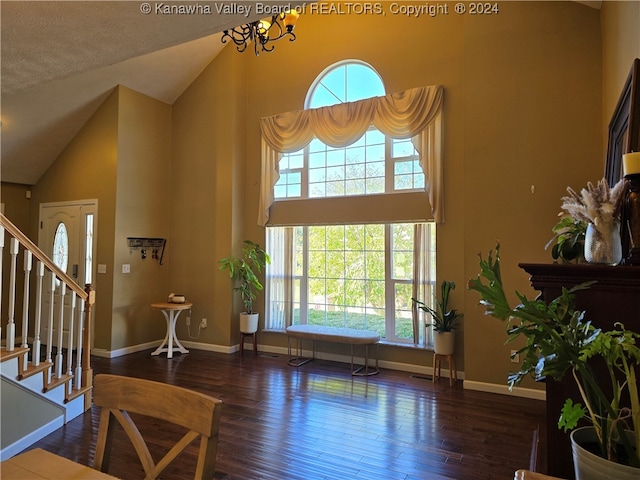 living room with dark wood-type flooring, high vaulted ceiling, and a chandelier