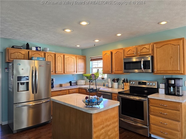 kitchen with dark wood-type flooring, appliances with stainless steel finishes, a kitchen island, and a textured ceiling