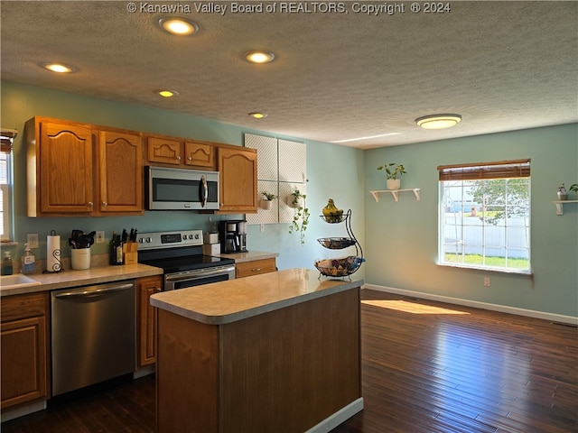 kitchen with dark wood-type flooring, a kitchen island, stainless steel appliances, and a textured ceiling