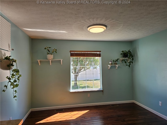 spare room with a textured ceiling and hardwood / wood-style floors