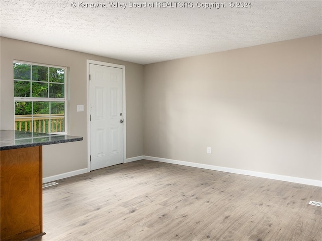 unfurnished dining area with light hardwood / wood-style floors and a textured ceiling